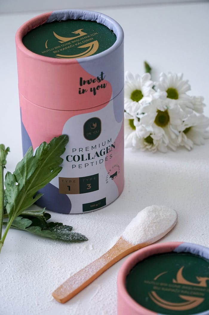 Elegant still life photo of collagen peptides product with green leaves and white flowers.